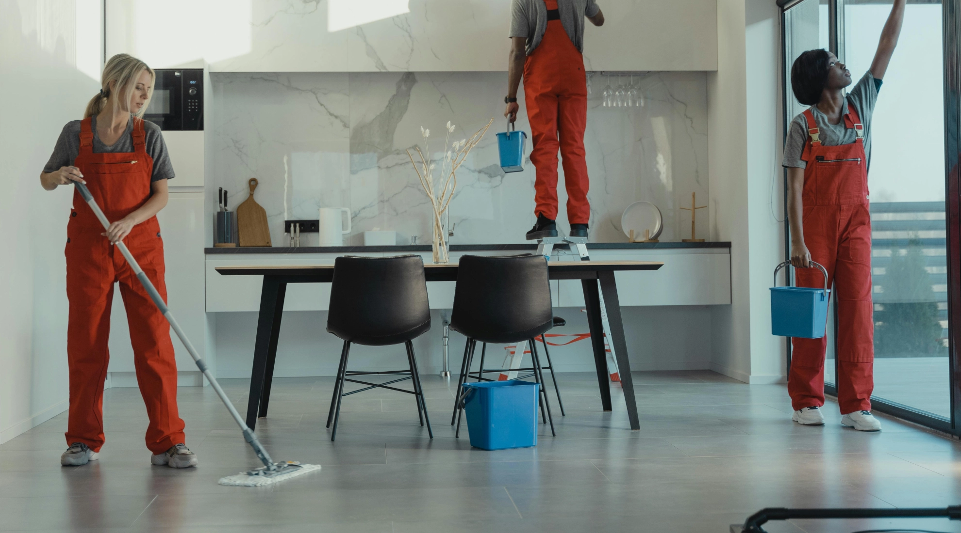 Team of professional cleaners in red uniforms mopping floors and cleaning windows in a modern office space – expert office cleaning services and commercial office cleaning.