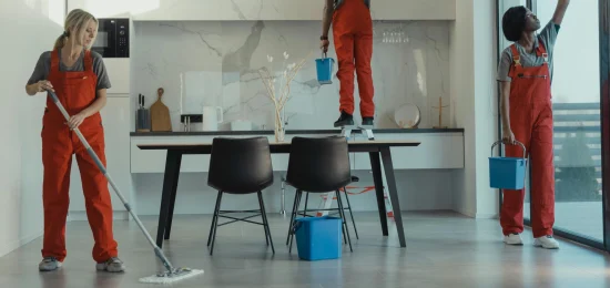 Team of professional cleaners in red uniforms mopping floors and cleaning windows in a modern office space – expert office cleaning services and commercial office cleaning.